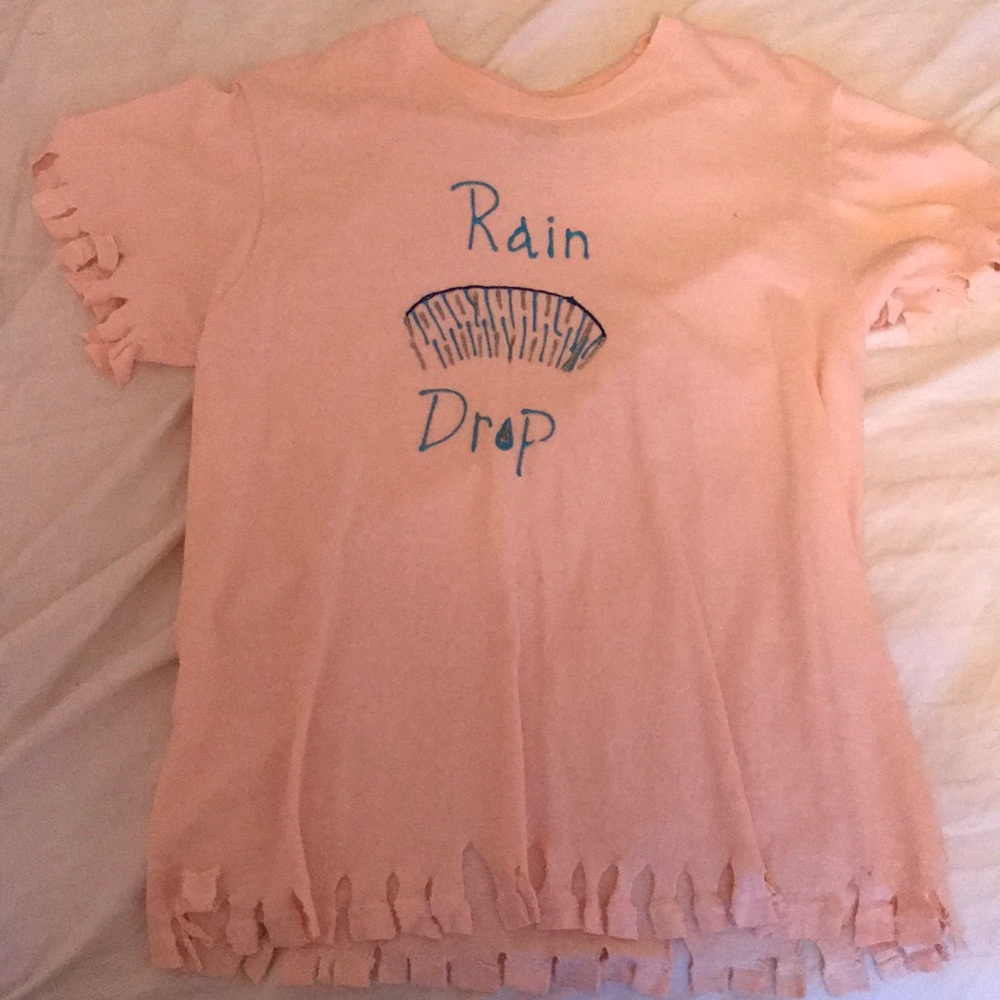 A cream shirt with silver and blue writing on it.